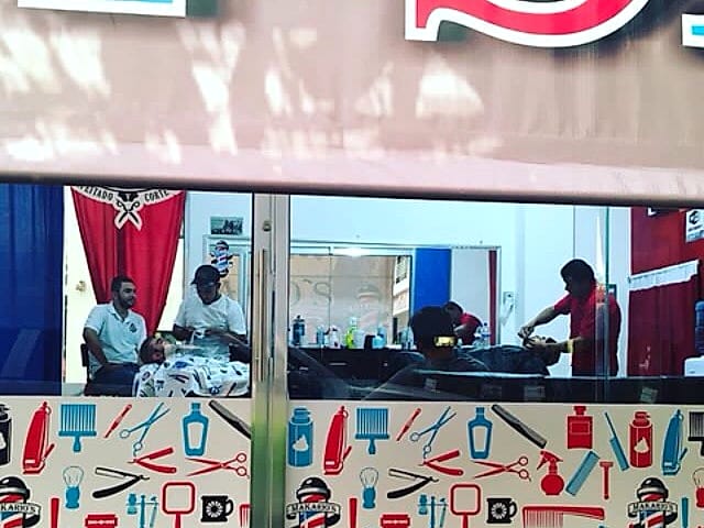 Barberos trabajando vistos desde la vitrina