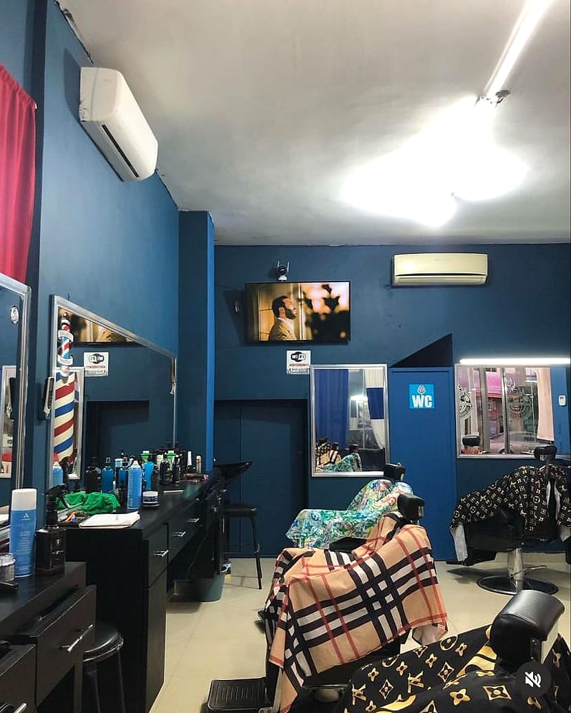 Interior de Makario's Barber Shop con muros azules y sillas de barbero