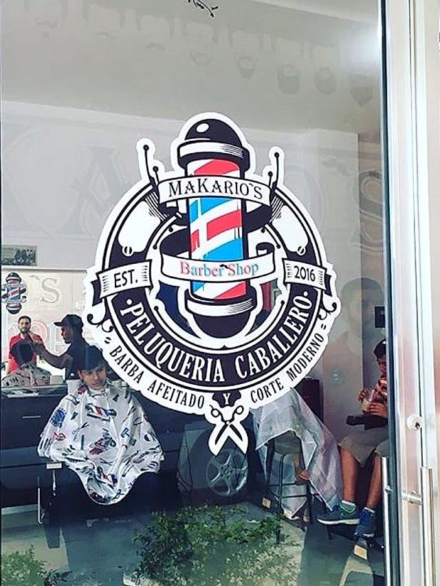 Logotipo de Makario's Barber Shop en la vitrina